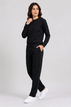 Woman wearing plain black tracksuit walking pose
